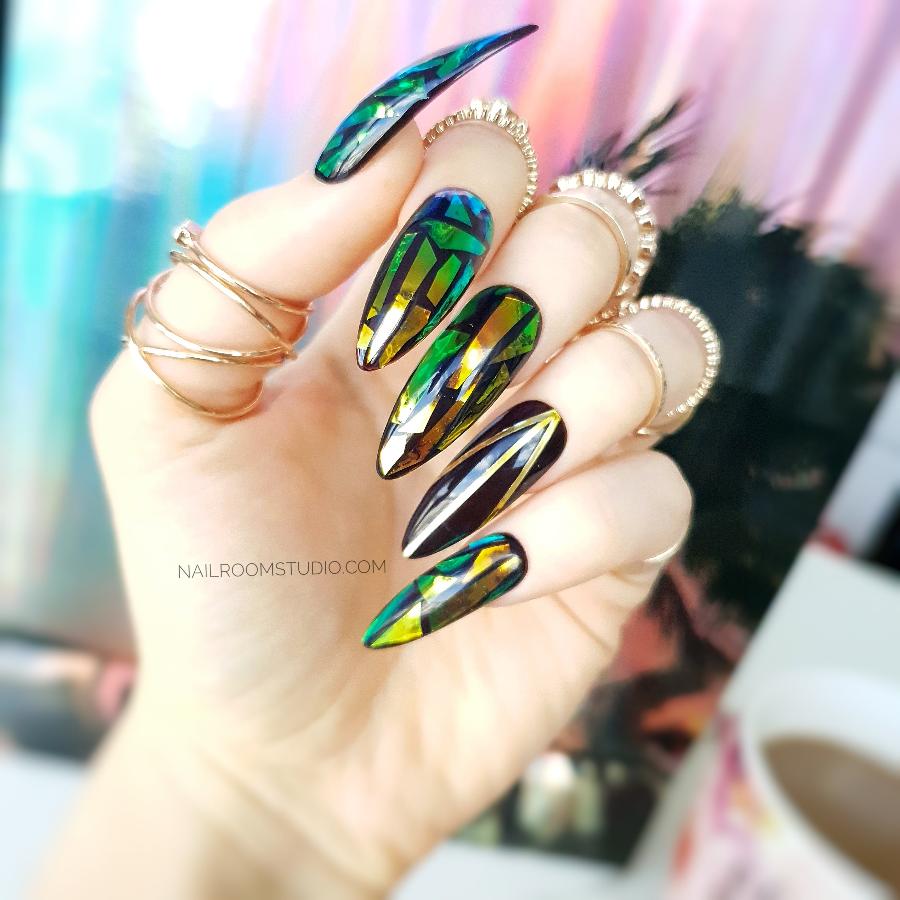Long stiletto nails in dark brown and black with an iridescent broken glass effect, designed by Nail Room Studio