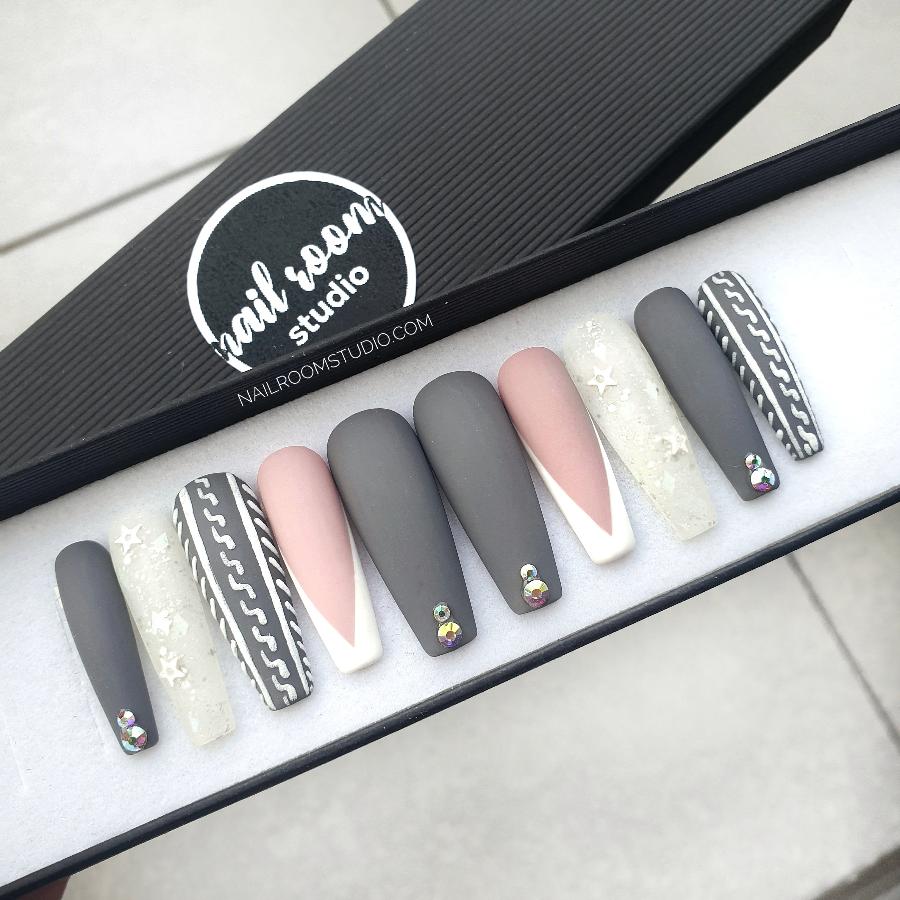 Gray and nude matte sweater nails with French tips and crystal accents. Ideal for Christmas and winter occasions by Nail Room Studio with frozen white design with stars