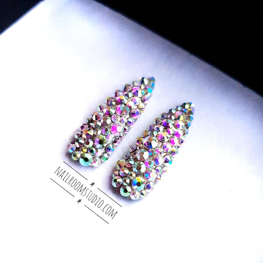 Long salon-quality stiletto nails decorated with authentic Swarovski crystals and a silver iridescent finish from Nail Room Studio