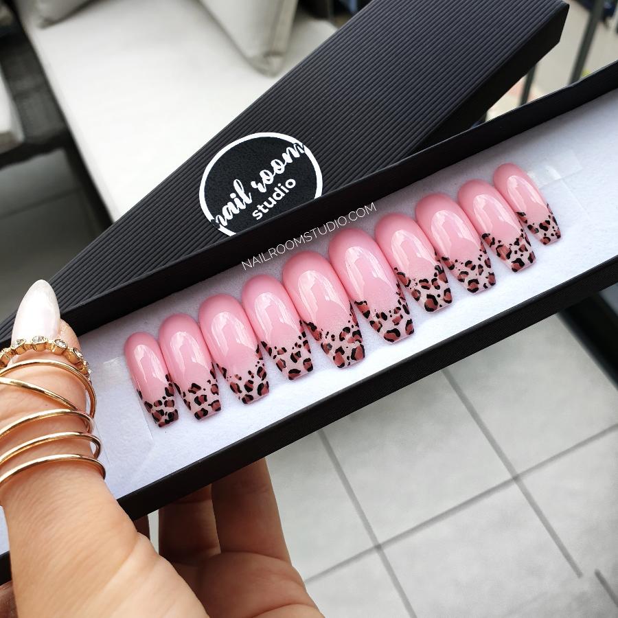 Pink kawaii-style nails with hand-painted leopard French designs, perfect for a playful vibe by Nail Room Studio