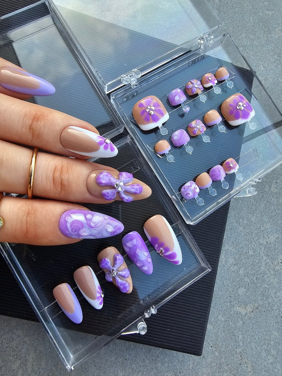 White women fingers with nude press on nails with 2D hand made floral accents in french style, in the background toes manicure in the same style