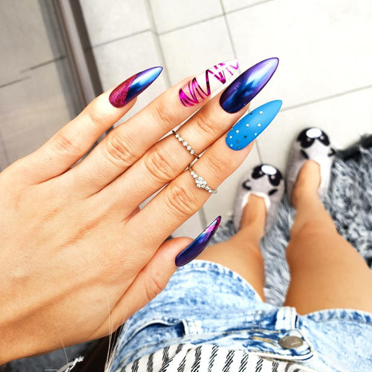 Navy blue stiletto nails with a matte chrome finish, accented by pink chrome stripes and blue glitter for a bold statement