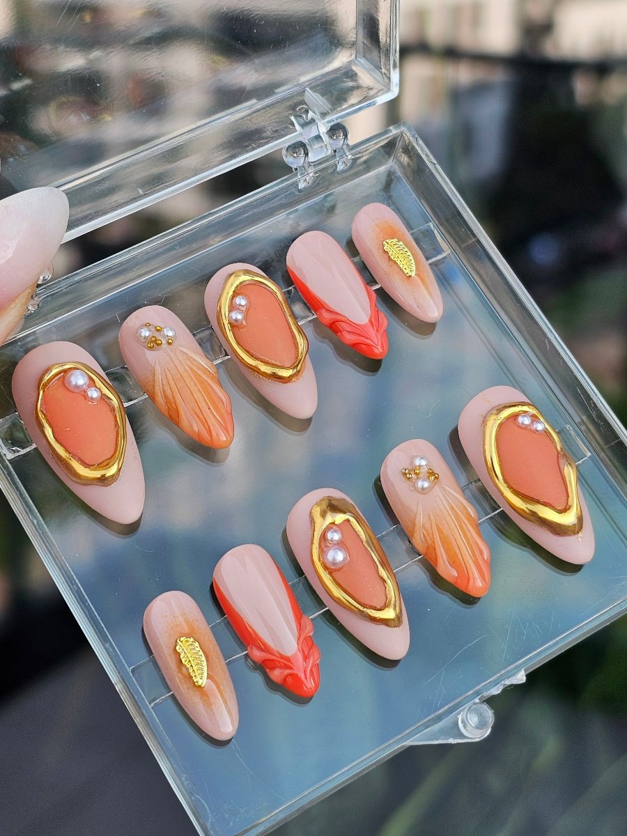 Handmade orange press on nails in 3D French style with gold feather accents, custom lengths and shapes, medium almond, worldwide shipping.