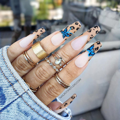 Set of 20 long sculpted coffin nails with a stunning panther handmade print on french tips, highlighted by blue butterfly motifs and stylish brown and beige accents from Nail Room Studio in Canada