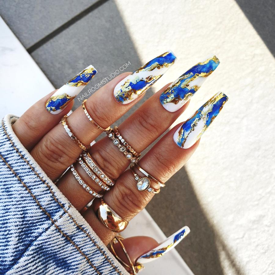 Navy blue long coffin nails by Nail Room Studio with gold chrome accents, marble effect, and wavy design for a luxurious look, ideal for mani-pedi set