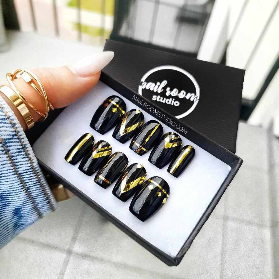 Glossy black coffin nails with gold chrome stripes and boho-inspired ethnic patterns by Nail Room Studio