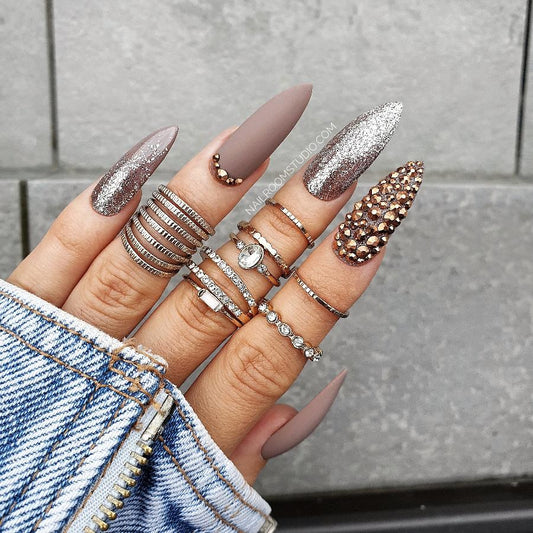 Cappuccino and hazel matte nails with gold and silver drum flakes, featuring a Swarovski crystal-filled accent nail by Nail Room Studio