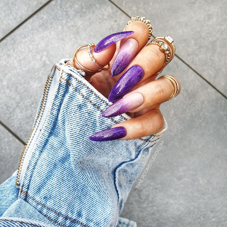 Long stiletto nails in a purple ombre with nude and glittery accents, crafted for those embracing the witchy vibe, exclusively by Nail Room Studio