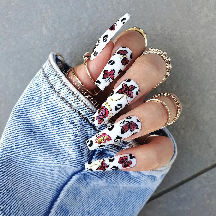 Chic white nails showcasing red floral and butterfly designs, perfect for a romantic look, false nails set with dalmatian spots design from Nail Room Studio