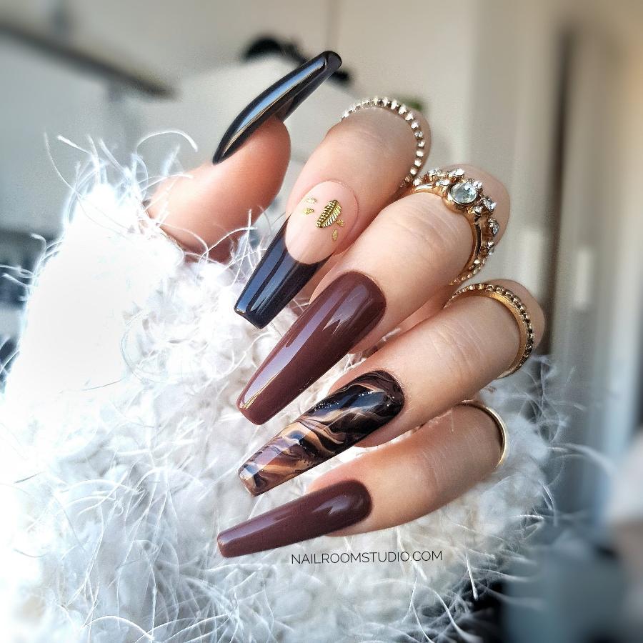 Brown beige marble nails with a glossy finish, featuring a small gold feather and French accent on one nail, perfect for matching manicure and pedicure by Nail Room Studio