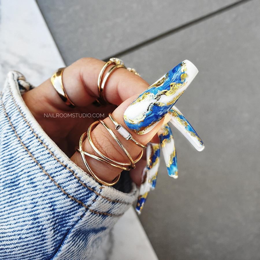 Stylish long sculpted coffin nails by Nail Room Studio in navy blue with gold chrome accents, wavy design, and marble effect, perfect as a press-on mani-pedi cruelty free set