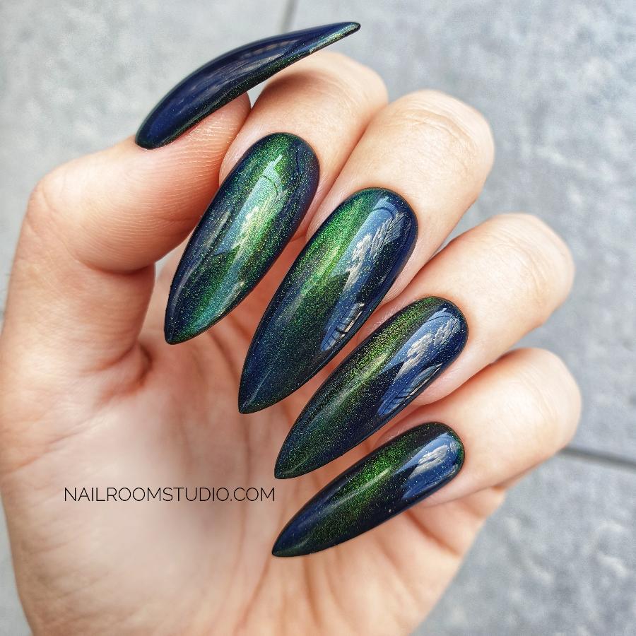 Gothic-inspired long stiletto nails in dark green with a cat-eye shimmer for a mystical vibe by Nail Room Studio