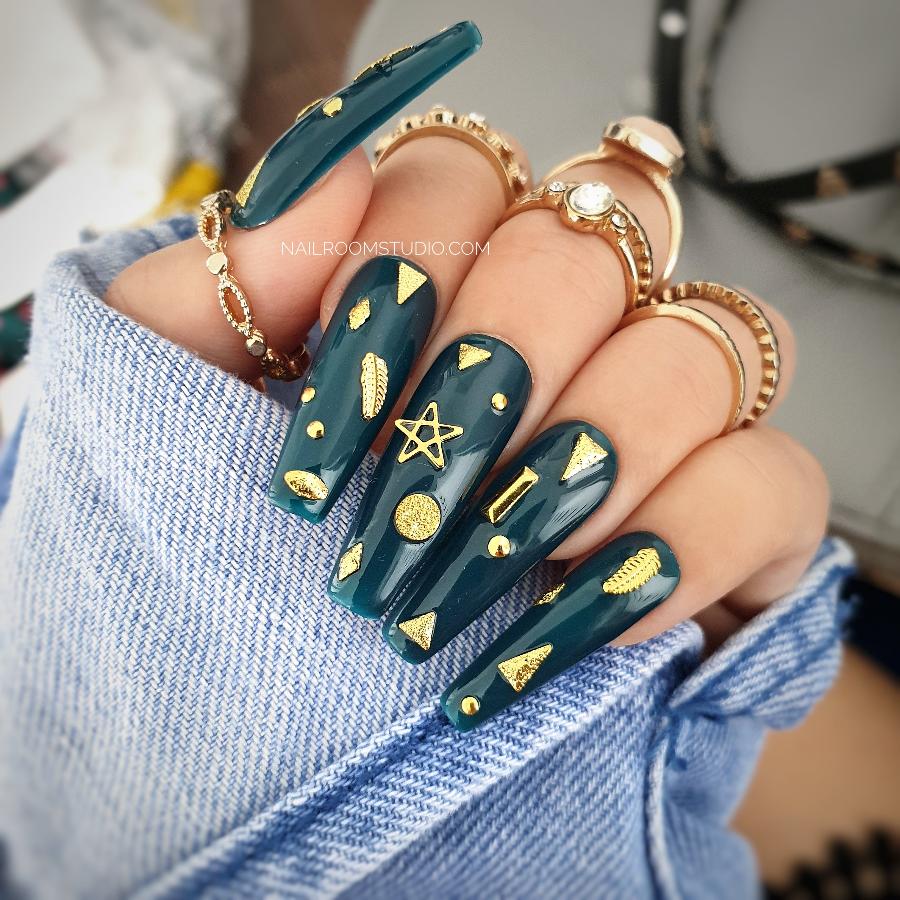 Nail Room Studio long sculpted coffin nails in deep bottle green with gold metallic charms and star and moon designs, ideal for a witchy, celestial look