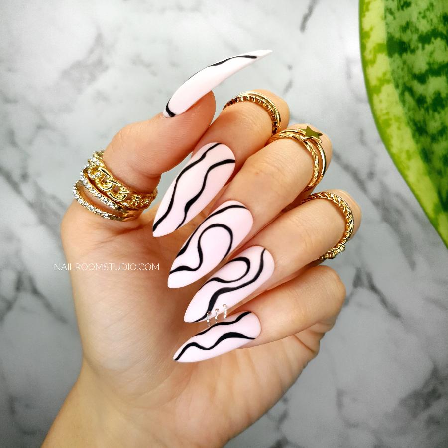 Powder pink long stiletto nails with black hand-painted waves, perfect for a fresh spring and summer manicure and pedicure from Nail Room Studio