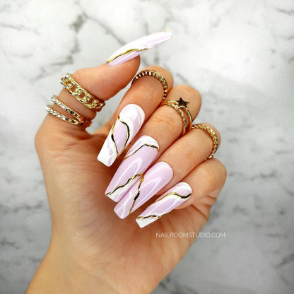 Long sculpted coffin nails with a soft pink and white blend, featuring a marble design with golden accents, and a glossy finish, perfect for stylish hand and toe tips with a unique wave pattern