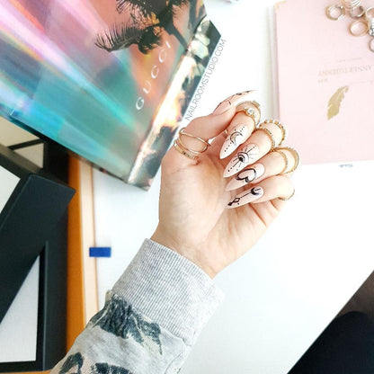 Witchy nude nails with delicate hand-painted designs of celestial elements like the moon and stars on a long stiletto shape by Nail Room Studio