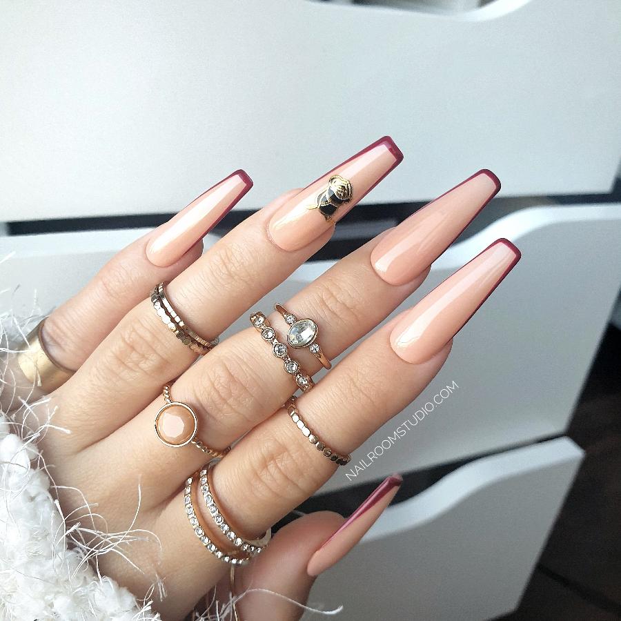 Witchy peachy nude glossy nails featuring burgundy French tips, black rose art, and golden highlights for a stylish, mysterious vibe by Nail Room Studio