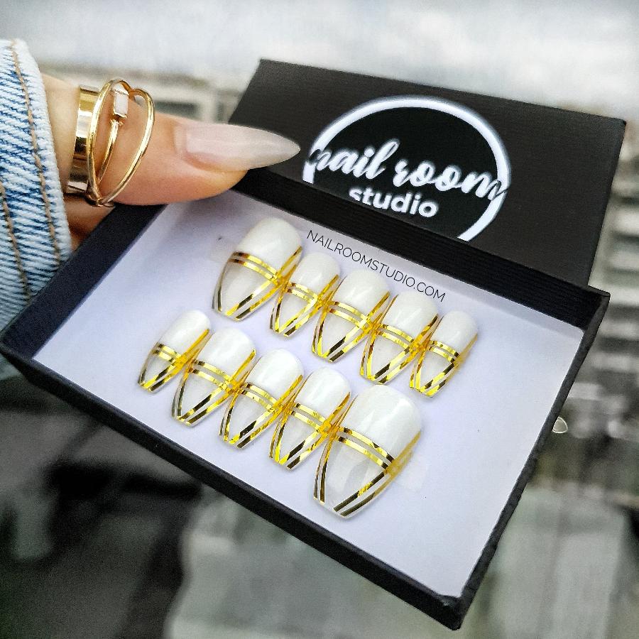 Stylish coffin nails in a transparent finish with eye-catching gold accents, perfect for a modern aesthetic by Nail Room Studio