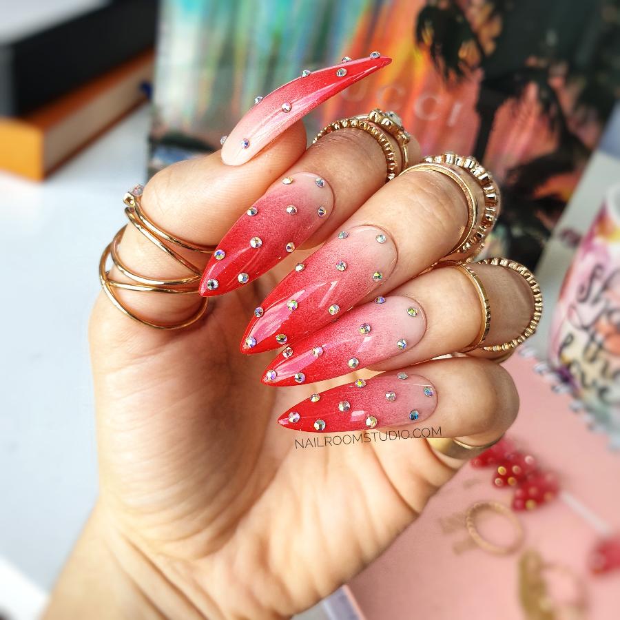 Long stiletto faux nails in a red and nude ombre with tiny silver crystals and a playful dotted pattern by Nail Room Studio