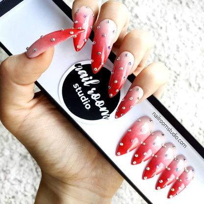 Custom stiletto nails with strawberry red ombre, dotted design, and tiny silver crystals by Nail Room Studio