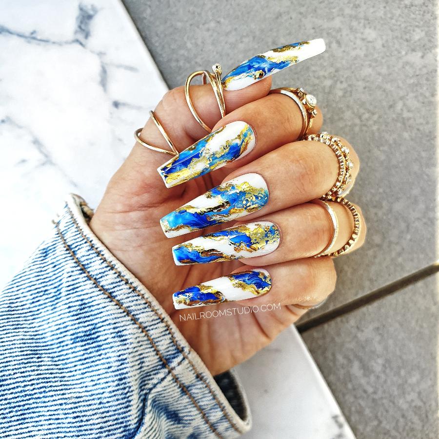 Exclusive navy blue and chrome nails by Nail Room Studio with marble effect, wavy design, and gold accents, suitable for matching mani-pedi nail kit