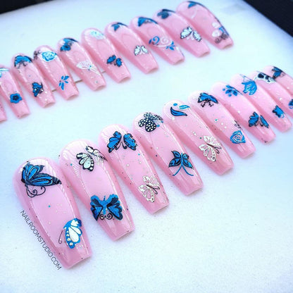 Vibrant pink summer nails in a full set of 20, showcasing long sculpted cupping with silver and blue butterfly accents, ready for the party on a beavh with girls from Nail Room Studio