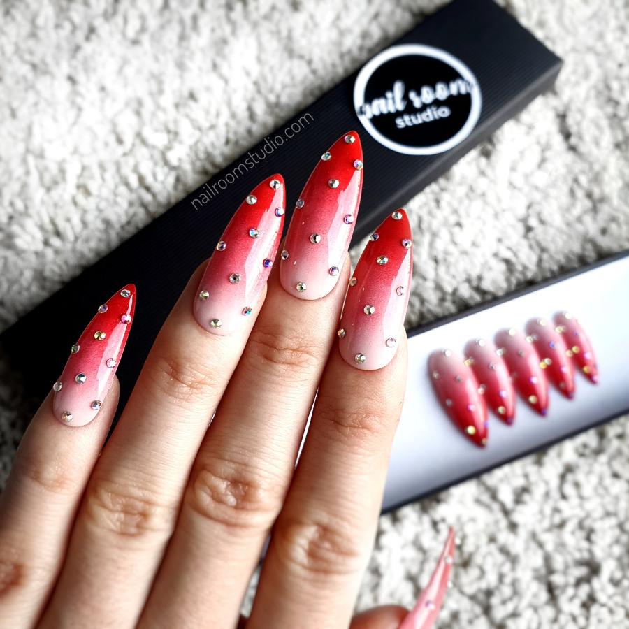 Ombre stiletto nails with strawberry red tones, small silver crystals, and dotted detail by Nail Room Studio