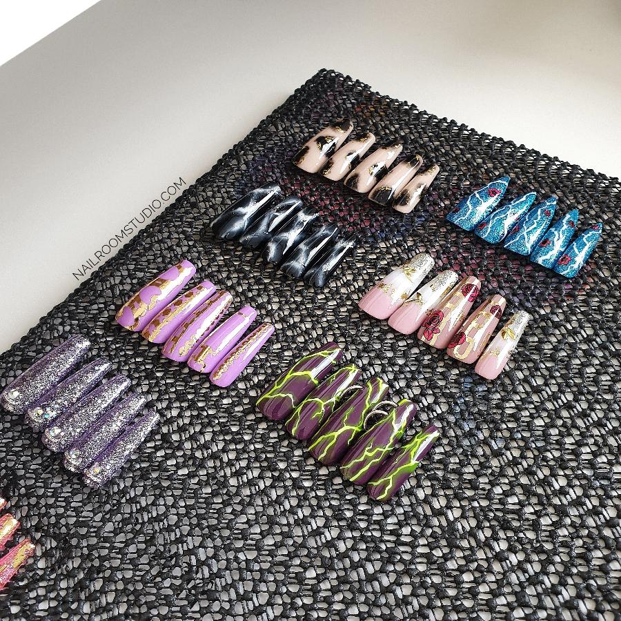 Extra long sculpted nails by Nail Room Studio in purple, pink, blue, black, and nude shades with lightning design, crystals, and giraffe detail