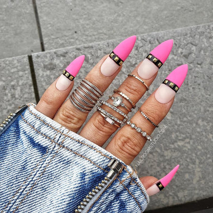 Long steel rose nails in ultra pink with nude tips and bold black and gold accents from Nail Room Studio, suitable for darker skin tones