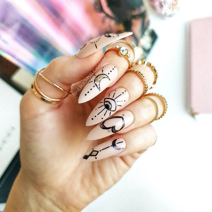 Long stiletto fairy-inspired nude nails with hand-painted designs of celestial themes including the sun, moon, and hearts by Nail Room Studio