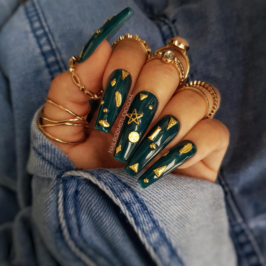 Nail Room Studio deep bottle green sculpted coffin nails with celestial decorations like stars and moons, accented with gold charms. Perfect witchy gothic style