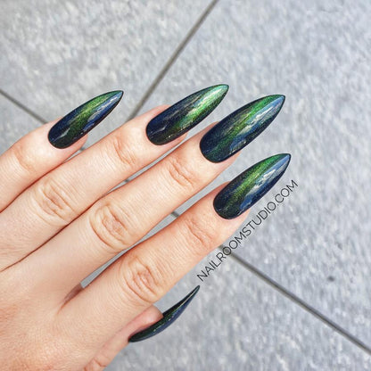 Dark green stiletto nails with a cat-eye effect, reflecting shimmer for a magical, witchy look by Nail Room Studio