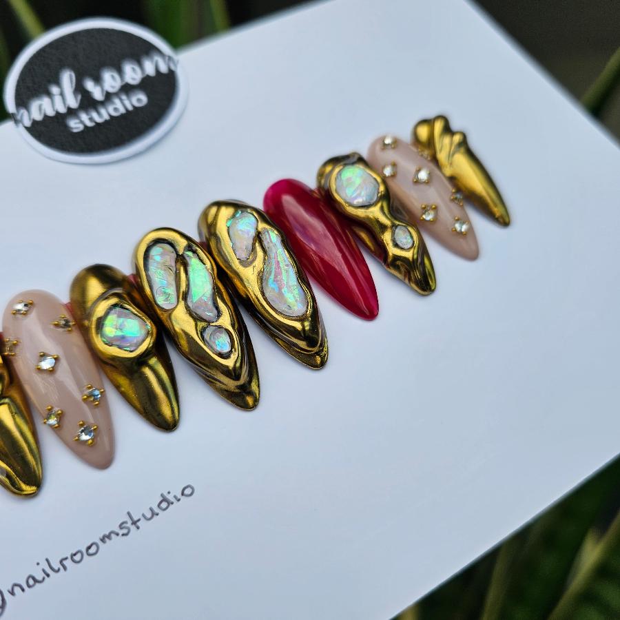 Luxurious handmade press-on nails featuring a golden chrome finish, adorned with crystal accents and a hint of matte nude, complemented by a partially transparent burgundy shade for a unique Halloween touch