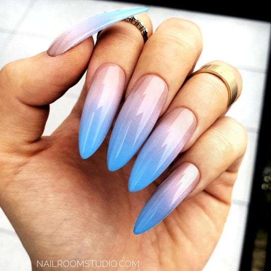 Baby Boomer press-on nails in powder pink with baby blue tips, designed in a long stiletto shape showcased on the hand of a white woman. Custom-made acrylic nails of salon quality