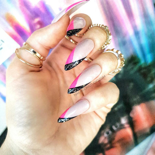 Hand with long stiletto nails in modern french style with nude nail bed and pink mixed with glittery black sharp tips