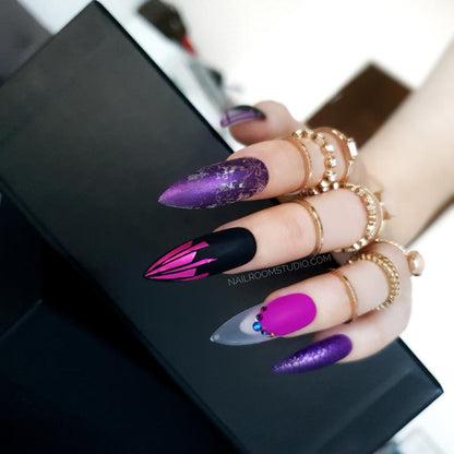 Matte violet stiletto nails with black and chrome accents, raindrop effects, and crystals, perfect for a dark, witchy style