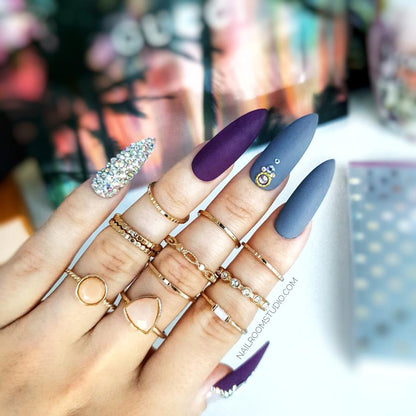 Deep matte purple nails paired with dark gray accents and adorned with shimmering Swarovski crystals for a luxurious look