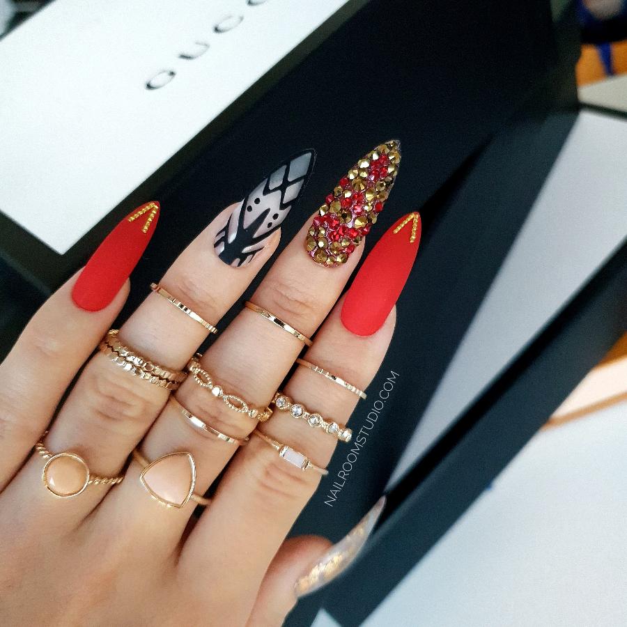 deep red femme fatale nails with lace accents, adorned with gold and red Swarovski crystals, featuring a bold chrome gold finish for a seductive, daring look