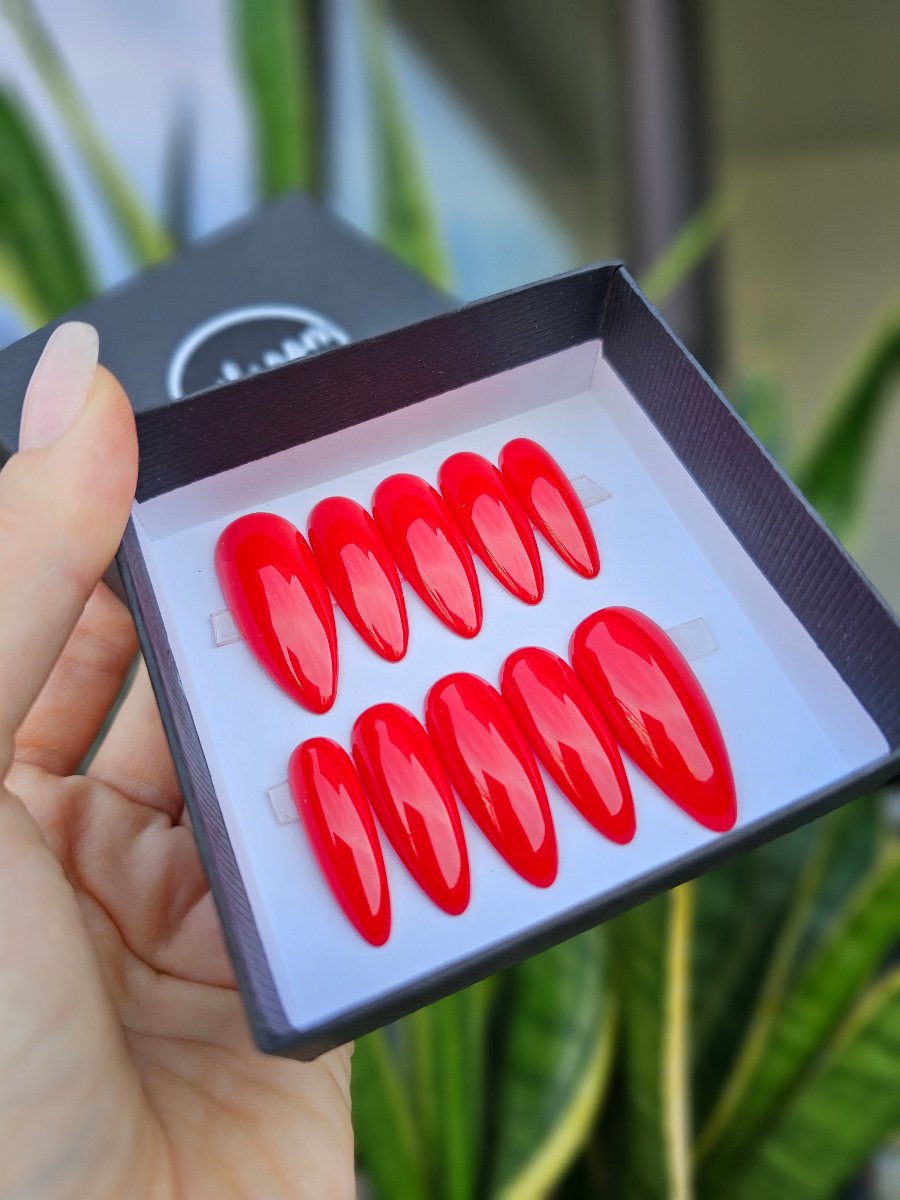 Exquisite collection of long almond press on nails in a vibrant Flamingo Red color, elegantly displayed in a premium black packaging with a branded logo