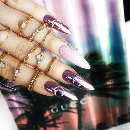 Stiletto nails with pink and white glitter ombre, chrome accents, and a mystical moon-inspired design