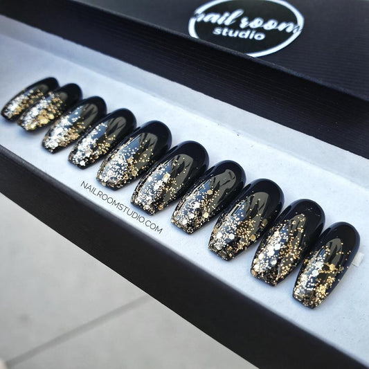 Glossy black coffin nails in a stylish black box, finished with a gold chrome ombre effect on the tips for extra sparkle