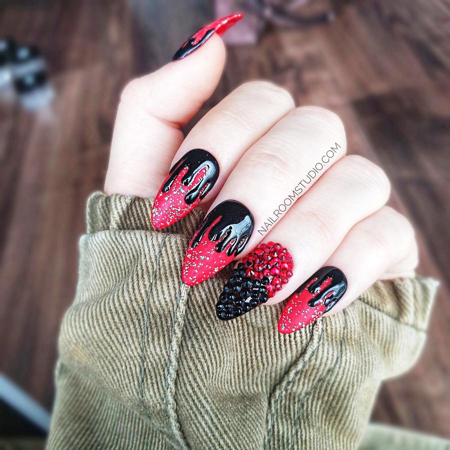 Gothic-themed Halloween press-on nails in deep red with black dripping design, featuring one glossy accent nail with dark Swarovski crystals, creating a bold witchy look on hands