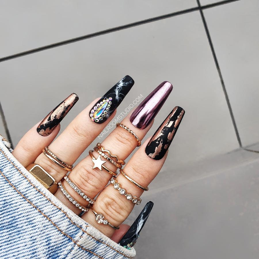 Long matte black coffin faux nails with rusty copper chrome accents, hand-painted black marble design, and embellished with Swarovski crystals