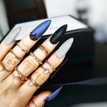 Dramatic stiletto nails in matte chrome featuring black Swarovski crystals and a sugar glitter effect for a striking finish