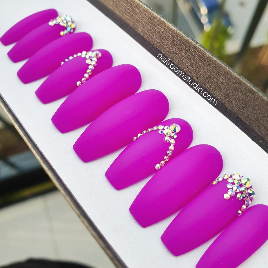 Eye-catching matte neon purple press-on nails embellished with opalescent Swarovski crystals in an intricate pattern. Long length options available, with international shipping to the USA