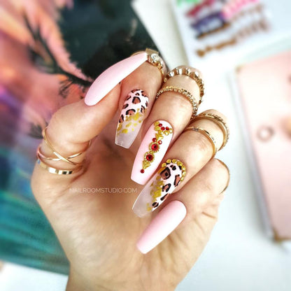 Matte nails with diagonal geometric French tips, hand-painted leopard print, and oriental accents featuring crystals and metallic elements for a unique, exotic look with sparkling red crystals