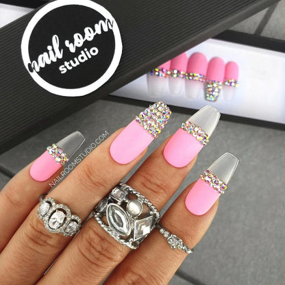 Elegant matte pink press-on nails in French style with Swarovski crystal accents, featuring opalescent silver on transparent French tips, shown on hands in a chic ballerina shape