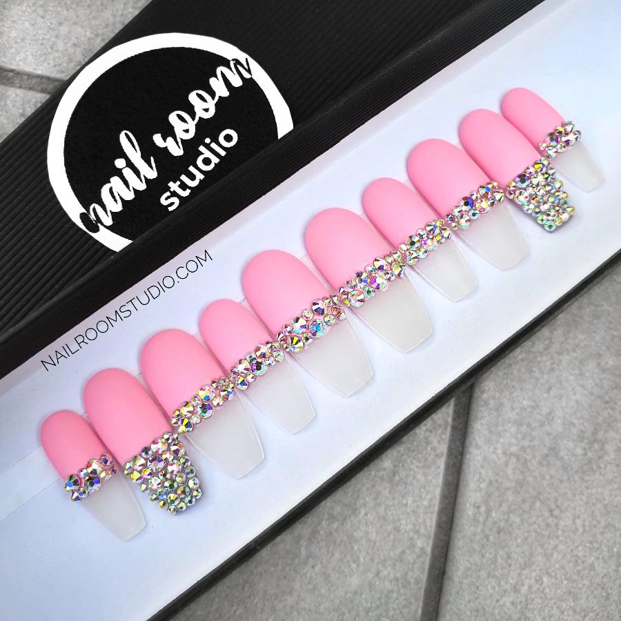 Elegant matte pink press-on nails in French style with Swarovski crystal accents, featuring opalescent silver on transparent French tips, shown on hands in a chic ballerina shape