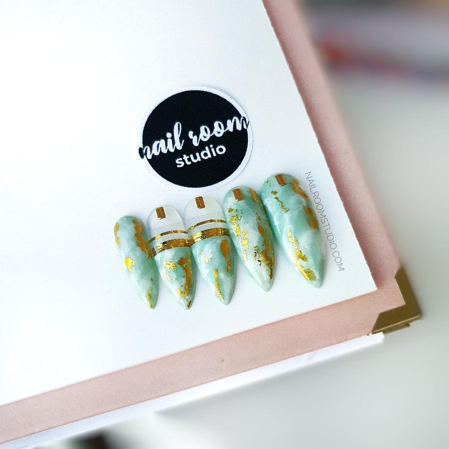 Mint and baby blue nails with a lightly ethnic vibe, featuring gold chrome stripes for an exotic touch