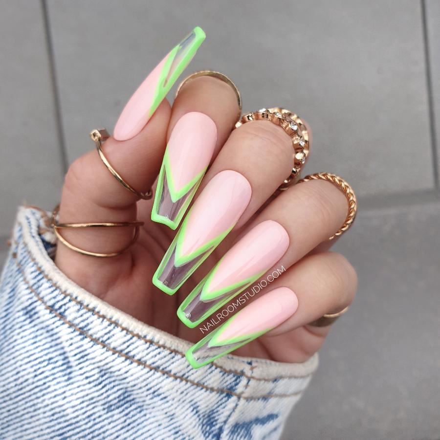 Stylish pink French nails with a bright neon green tip and transparent sections, creating a fresh, modern look on a hand with rings